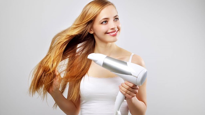 young woman drying hair with hair dryer